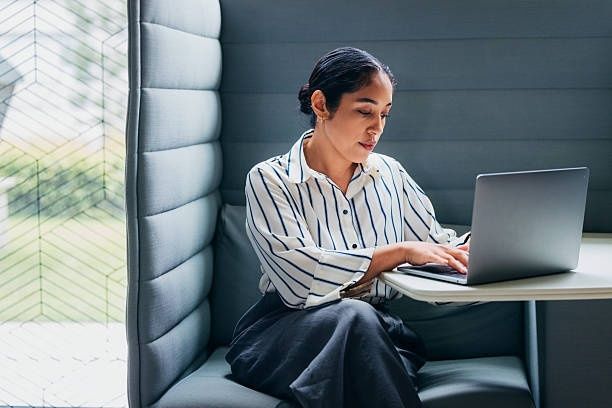 Vrouw werkt geconcentreerd op een laptop bij daglicht